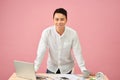 Portrait of a smiling young Asian designer working on a laptop while leaning on his desk Royalty Free Stock Photo