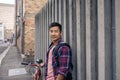 Smiling young man leaning against a wall with his bike Royalty Free Stock Photo