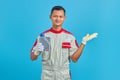 Portrait of smiling young Asian mechanic showing machine oil plastic bottle and pointing to copy space with palm over blue Royalty Free Stock Photo