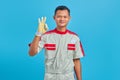 Portrait of smiling young Asian mechanic showing ok sign and looking at camera over blue background Royalty Free Stock Photo