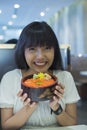 Portrait of smiling young asian woman holding japanese food dish Royalty Free Stock Photo