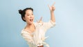 Portrait of a smiling young asian woman pointing fingers away at copy space isolated over blue background Royalty Free Stock Photo