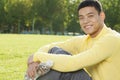 Portrait of smiling young athletic man sitting on the grass in a park in Beijing, looking at camera Royalty Free Stock Photo