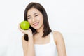 Portrait of smiling young beautiful Asian woman with healthy teeth holding green apple and looking at camera isolated over white Royalty Free Stock Photo