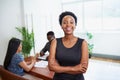 Portrait of a smiling young Black business woman arms folded in boardroom Royalty Free Stock Photo