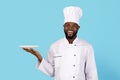 Portrait Of Smiling Young Black Chef In Uniform Holding Empty Plate Royalty Free Stock Photo