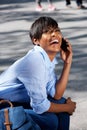 Smiling young black lady sitting outside and talking on cell phone Royalty Free Stock Photo