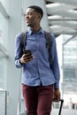 Smiling young black man traveling with bags and mobile phone Royalty Free Stock Photo