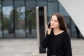 Portrait of a smiling young business woman near the office talking on a smartphone about financial matters Royalty Free Stock Photo