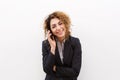 Smiling young business woman talking on cell phone by white background Royalty Free Stock Photo