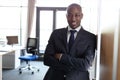 Portrait of smiling young businessman standing arms crossed leaning on cupboard in office Royalty Free Stock Photo