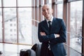 Portrait of smiling young businessman standing arms crossed leaning on cupboard in office Royalty Free Stock Photo