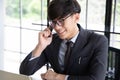 Portrait of a smiling young businessman  talking on his smartphone while he working , sitting in his office at desk wearing a blac Royalty Free Stock Photo