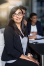 Succeeding is my top priority. Portrait of a smiling young businesswoman sitting in an office with colleagues in the Royalty Free Stock Photo