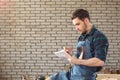 Portrait of smiling young carpenter in interior of workshop with notebook in his hands Royalty Free Stock Photo