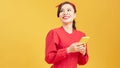 Portrait of a smiling young casual asian woman looking at mobile phone isolated over yellow background Royalty Free Stock Photo