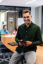 Portrait of smiling young caucasian businessman with digital tablet while colleagues in background Royalty Free Stock Photo