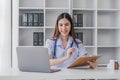 Portrait of smiling young Caucasian female doctor or nurse in white medical uniform in clinic Royalty Free Stock Photo