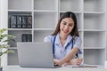 Portrait of smiling young Caucasian female doctor or nurse in white medical uniform in clinic Royalty Free Stock Photo