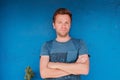 Portrait of smiling young caucasian man standing near blue wall with freen leaf