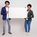 Portrait of smiling young colleagues showing blank poster while advertising over white background Royalty Free Stock Photo
