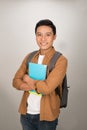 Portrait of smiling young college Asian student with books and backpack against white background