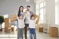 Portrait of smiling young couple with little kids in their new home on moving day Royalty Free Stock Photo