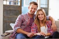 Portrait Of Smiling Young Couple Sitting On Sofa At Home Royalty Free Stock Photo