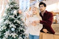 Portrait of smiling young couple using smartphone together standing with paper bags in hall of celebrate shopping mall Royalty Free Stock Photo