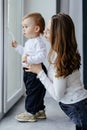 Portrait of a smiling young cute mother and her son playing near the window in a room. Sunny day outside. True mother love Royalty Free Stock Photo