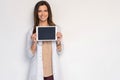 Portrait of smiling young doctor in white coat showing the screen of digital tablet in her hand. Royalty Free Stock Photo