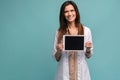 Portrait of smiling young doctor in white coat showing the screen of digital tablet in her hand. Royalty Free Stock Photo
