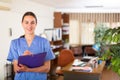 Portrait of a smiling young female doctor taking important notes while standing in the office Royalty Free Stock Photo