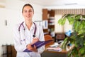 Portrait of a smiling young female doctor taking important notes while standing in the office Royalty Free Stock Photo