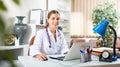 Smiling young female doctor working with laptop in office Royalty Free Stock Photo