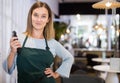 Smiling female hairdresser standing with electric hair clipper in barbershop