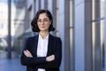 Portrait of a smiling young female lawyer standing outside the courthouse in a business suit, arms folded across her Royalty Free Stock Photo