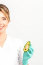 Portrait of smiling young female nutritionist doctor with organic avocado fruits posing at camera on white background Royalty Free Stock Photo
