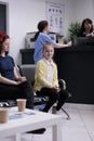 Portrait of smiling young girl with her mother sitting in hospital lobby waiting to see pediatric doctor. Parent with