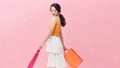 Portrait of a smiling young girl holding shopping bags and looking away at copy space isolated over pink background Royalty Free Stock Photo