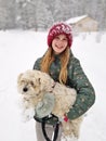 Portrait of A Smiling young girl holding up her Extremely Shaggy Dog Whose Paws are Caked in Snow