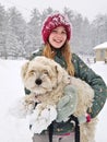 Portrait of A Smiling young girl holding up her Extremely Shaggy Dog Whose Paws are Caked in Snow