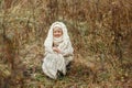 Portrait of a smiling young girl sitting in a park wrapped in a white blanket