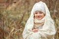 Portrait of a smiling young girl sitting in a park wrapped in a white blanket