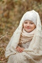 Portrait of a smiling young girl sitting in a park wrapped in a white blanket