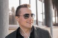 Portrait of a smiling young guy of European appearance, an attractive businessman in sunglasses, listening to music in headphones Royalty Free Stock Photo