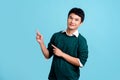 Portrait of smiling young handsome Asian man in green casual shirt pointing to empty copy space isolated on light blue background Royalty Free Stock Photo