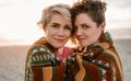 Smiling young lesbian couple wrapped in a blanket at sunset Royalty Free Stock Photo