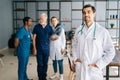 Portrait of smiling young male doctor wearing white uniform standing in medical meeting office, looking at camera. Royalty Free Stock Photo