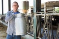 Farmer with milk churn standing near cowshed at dairy farm Royalty Free Stock Photo